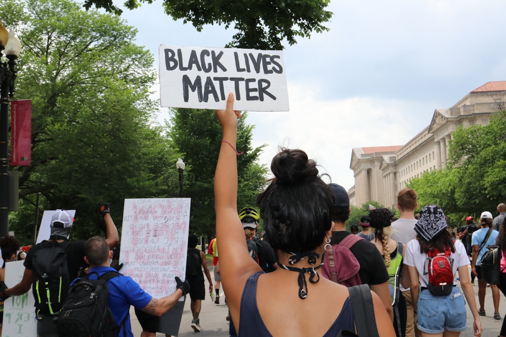 woman in blue spaghetti strap top holding white and black signage