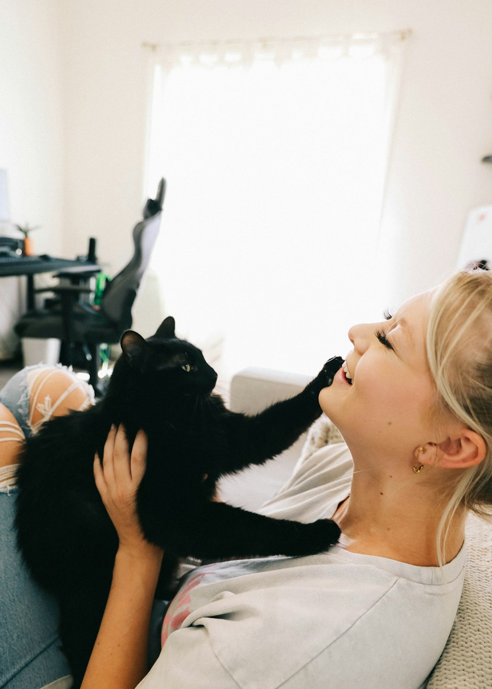 woman in white shirt holding black cat