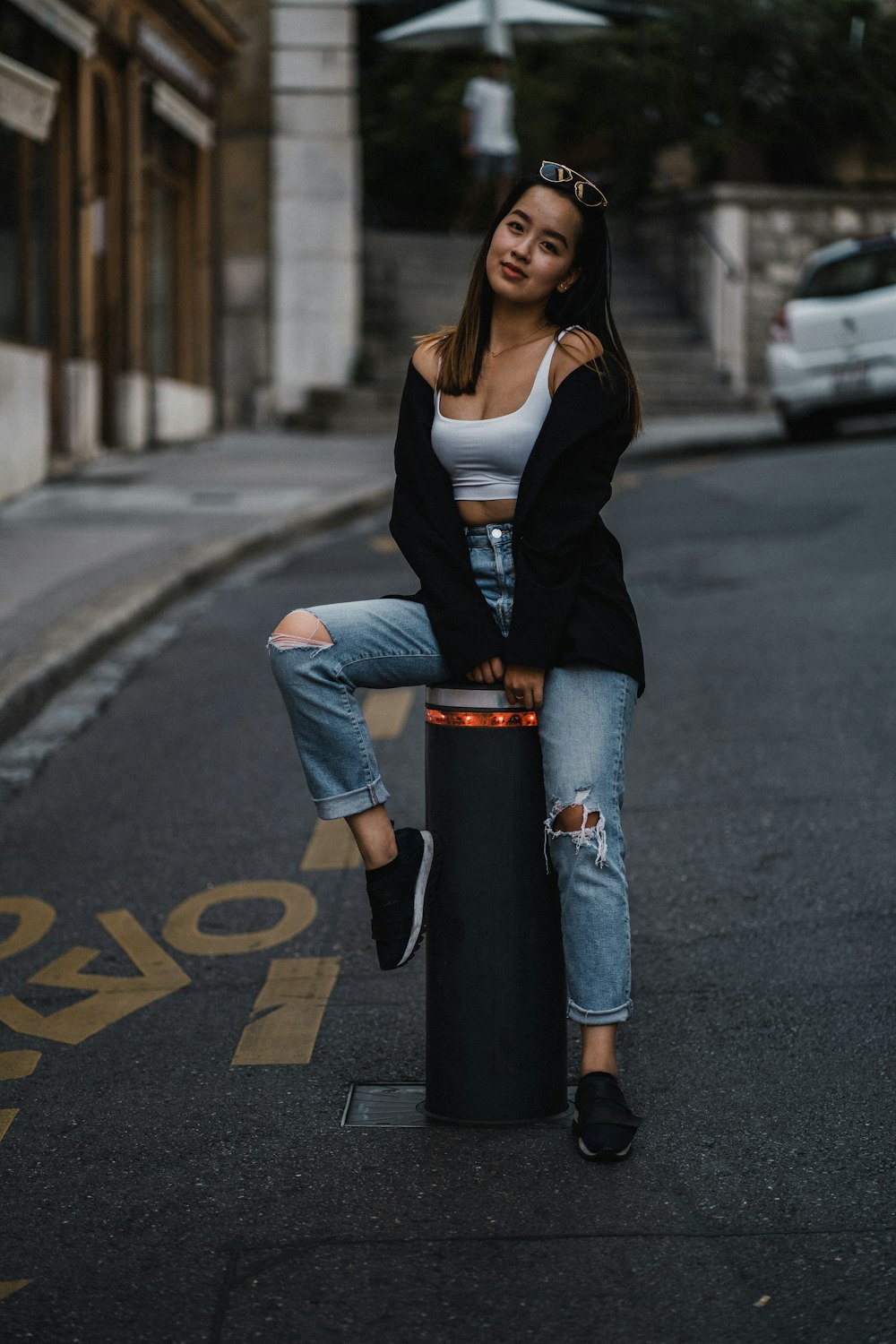 woman in black blazer and blue denim jeans standing on road during daytime