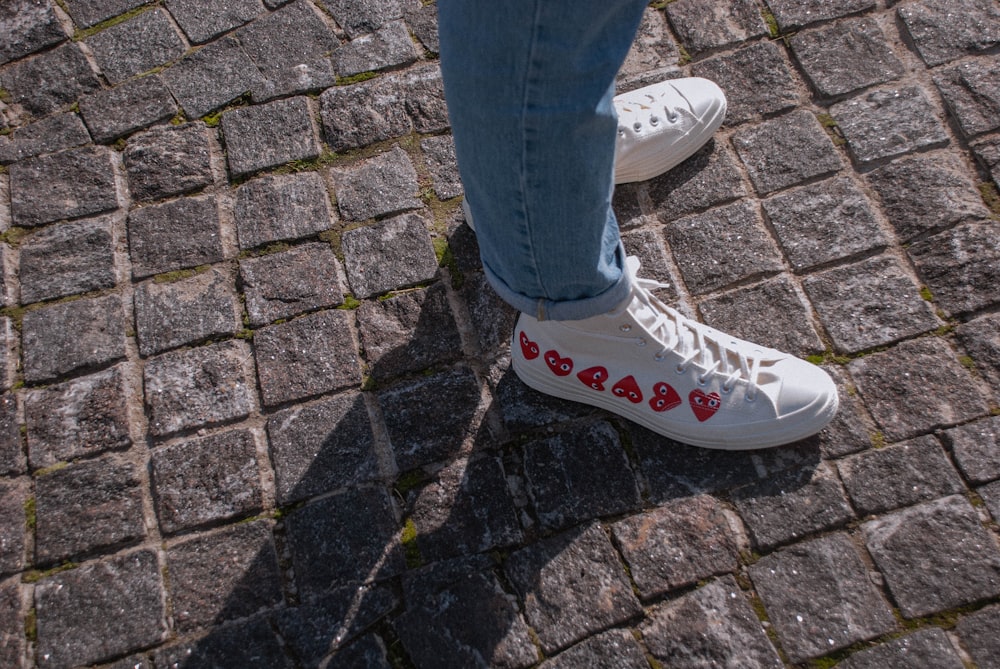 person in blue denim jeans and white converse all star high top sneakers