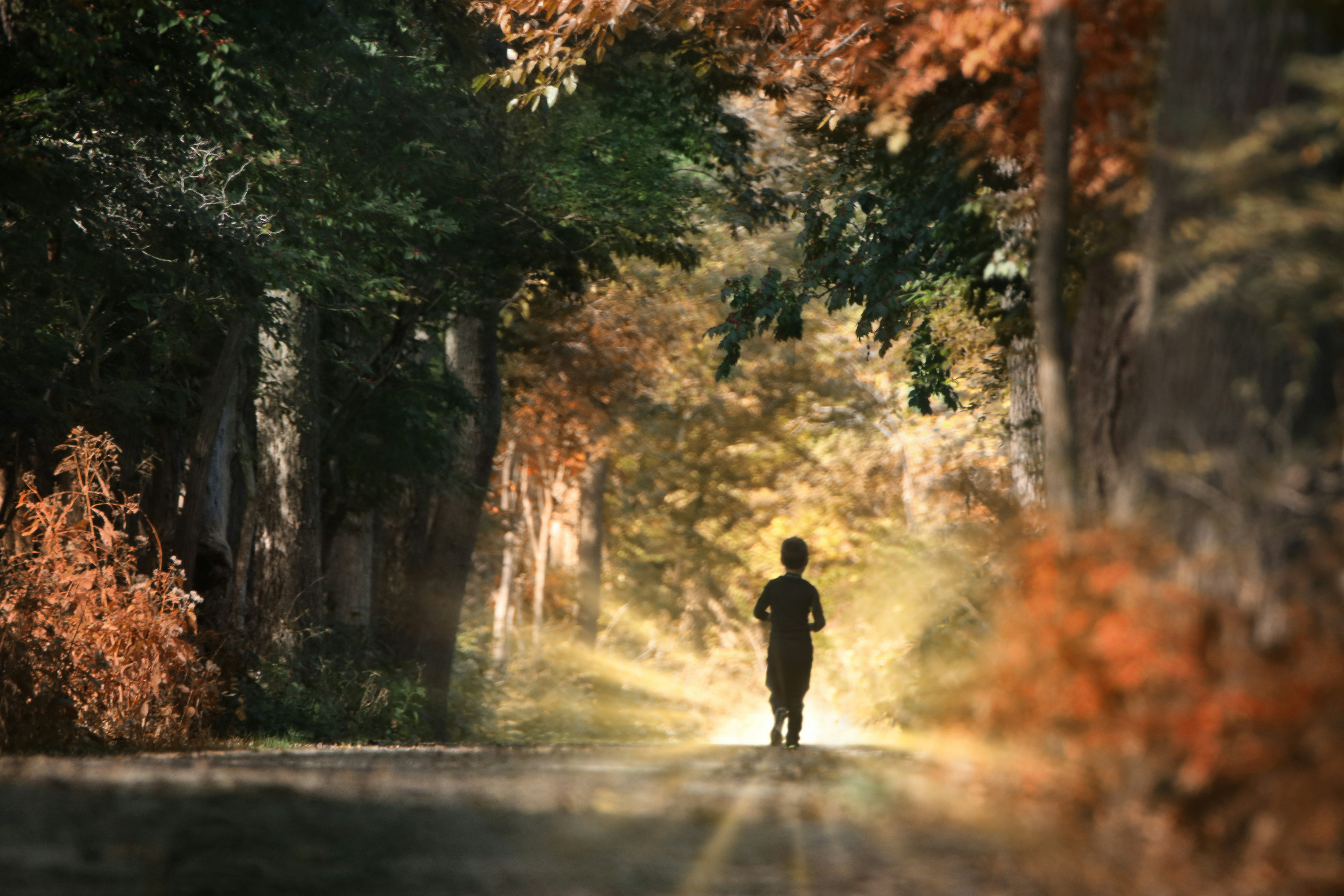 man in black jacket walking on road during daytime