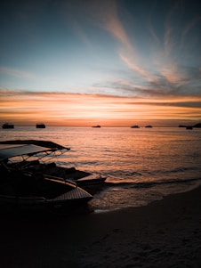 white and black boat on sea shore during sunset