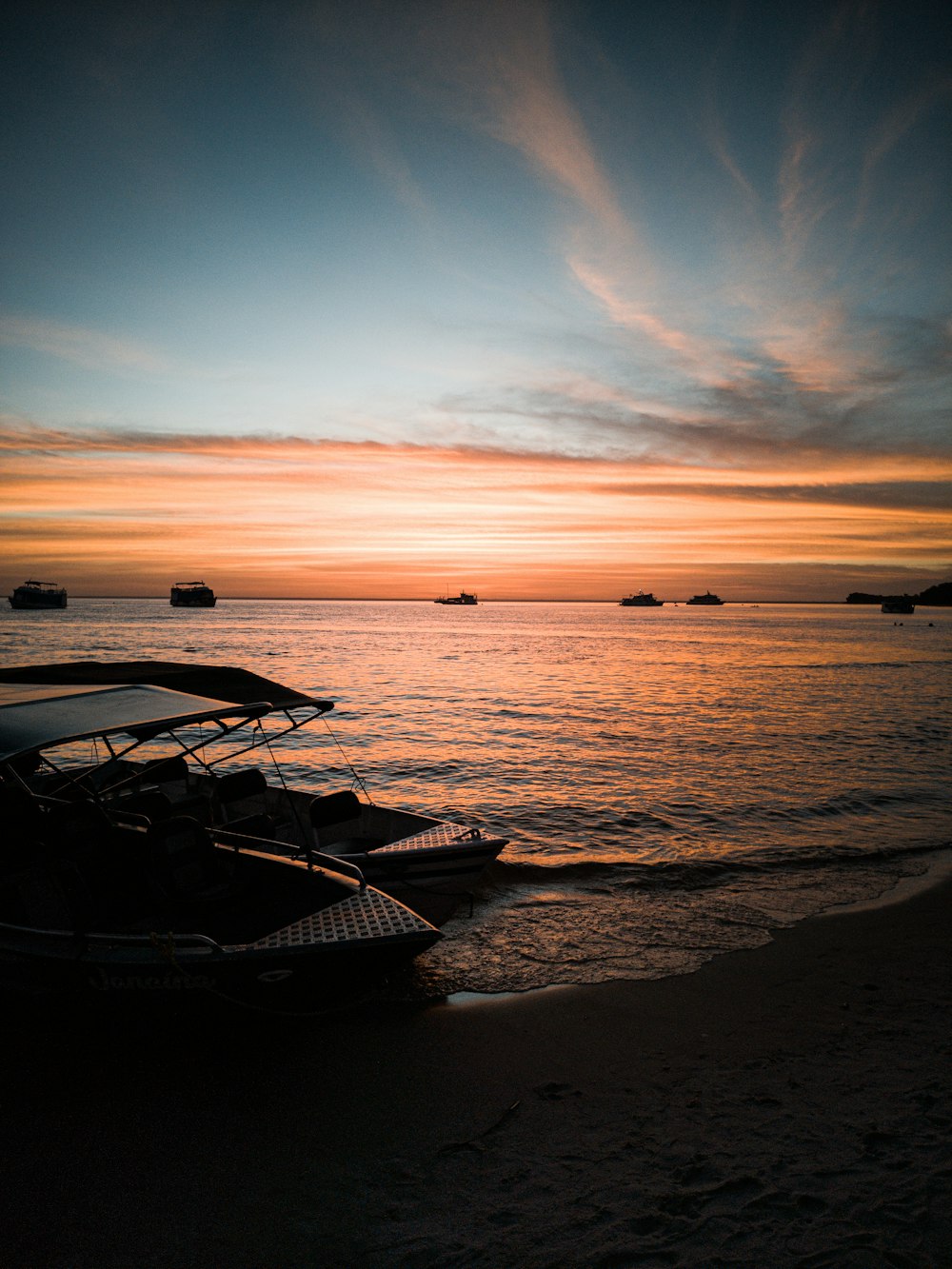 white and black boat on sea shore during sunset