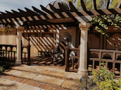 Handcrafted pergola casting soft shadows over an organic stone patio at sunset.