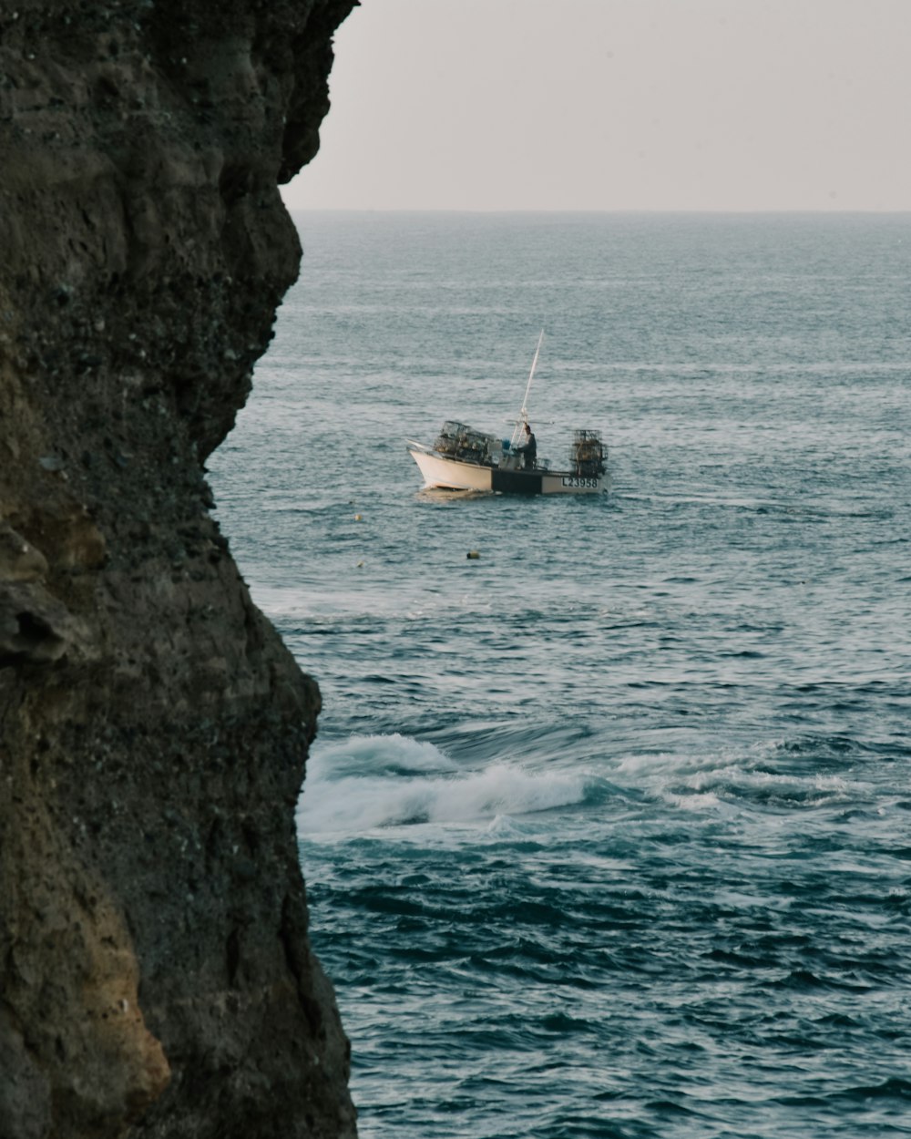 white boat on sea beside brown rock formation during daytime