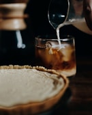 Close-up of a fresh pastry on a plate next to a glass of cold brew coffee.