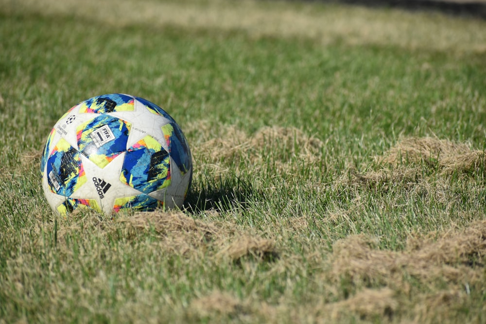 blue white and red soccer ball on green grass field during daytime