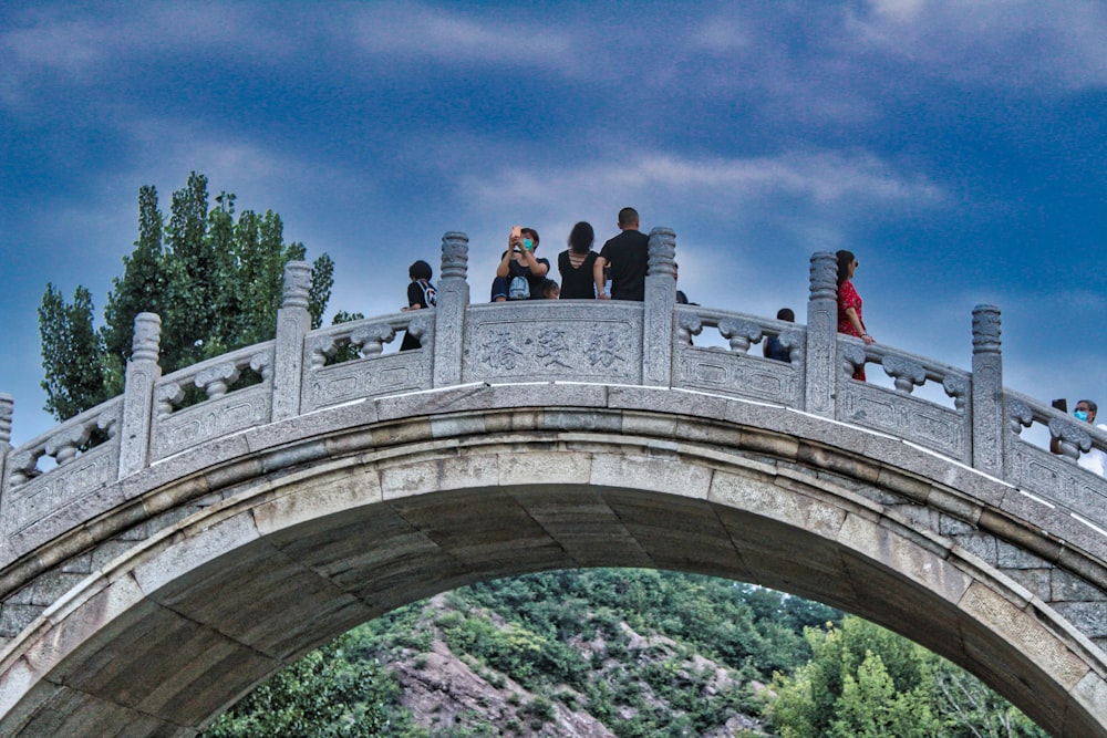 people walking on arch bridge under blue sky during daytime