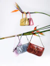 brown leather sling bag hanged on green and red clothes hanger