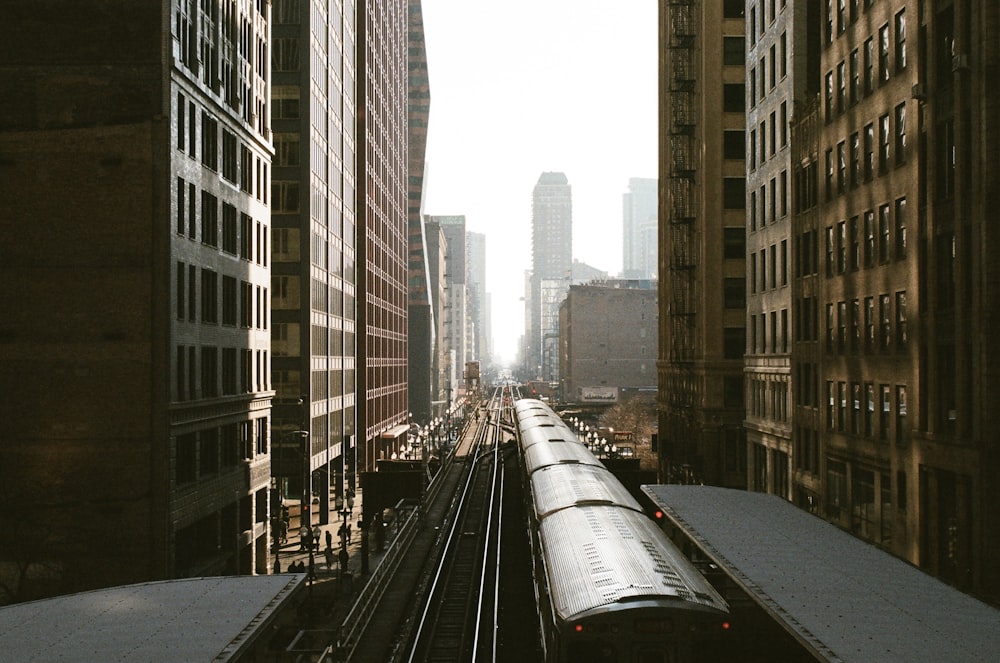 black and white train on rail road between high rise buildings during daytime