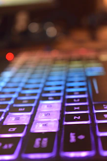 Close-up of hands typing on a modern keyboard with a vibrant background.