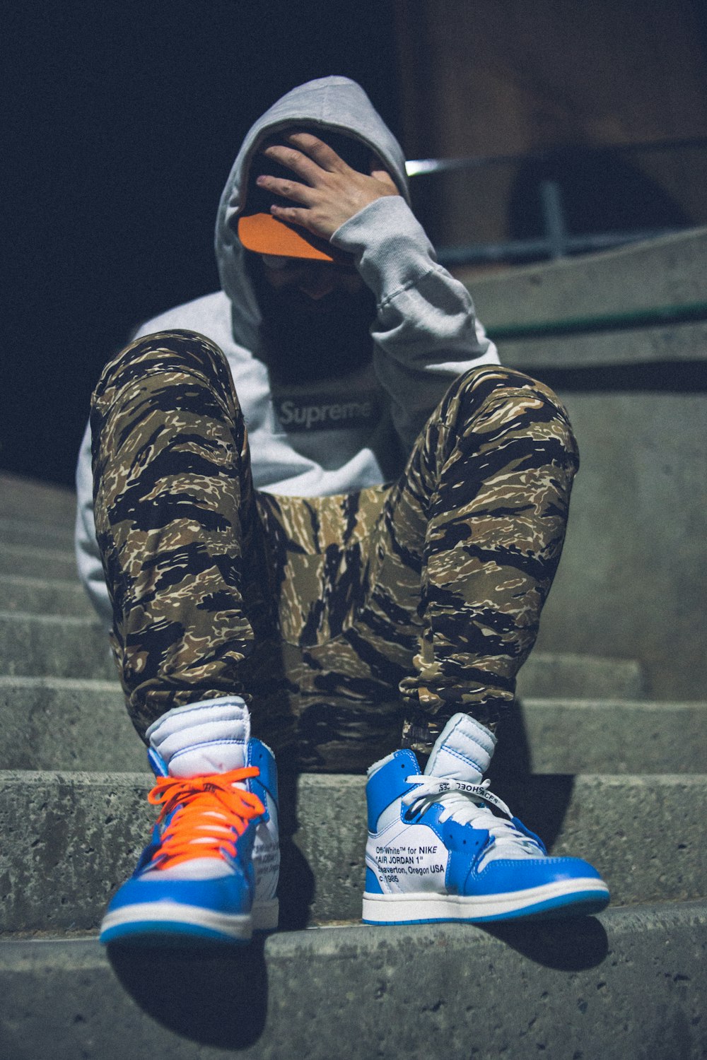 person in black and brown camouflage jacket and blue and white nike shoes