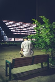 man in white shirt sitting on brown wooden bench