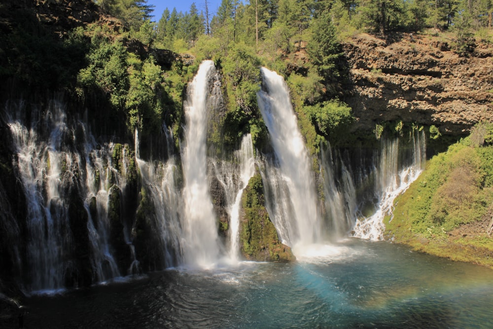 waterfalls in the middle of green trees during daytime