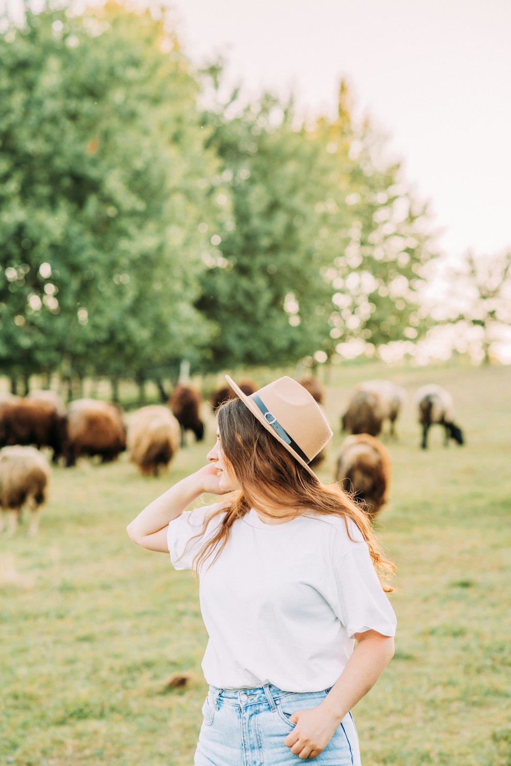 woman in white long sleeve shirt wearing white hat standing on green grass field during daytime