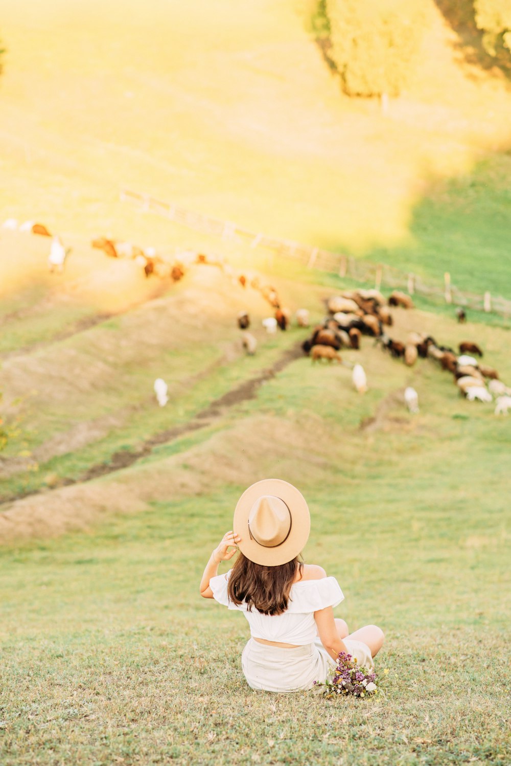 woman in white sun hat standing on green grass field during daytime