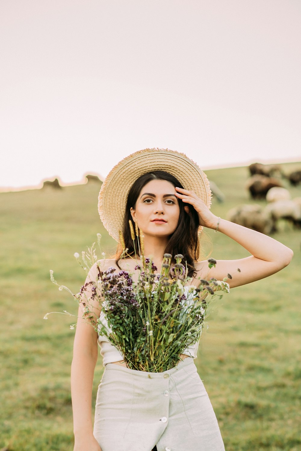 Femme en robe blanche à fleurs portant un chapeau de paille marron