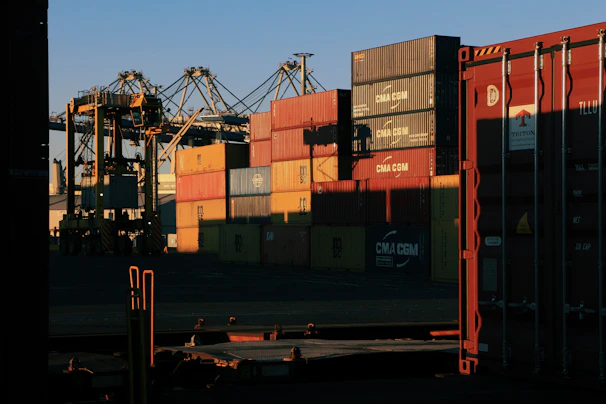 Stacks of shipping containers neatly arranged at a bustling international port.
