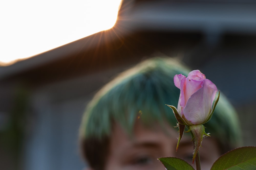 pink flower in front of man