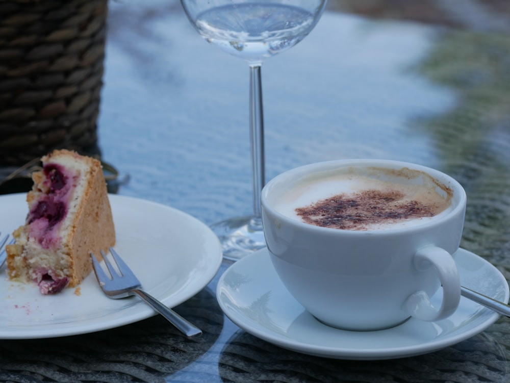 white ceramic cup on white ceramic saucer beside stainless steel fork