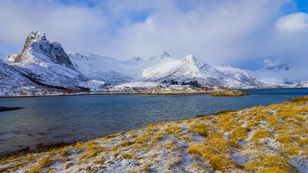 snow covered mountain near body of water during daytime