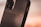 A close-up view of a smartphone case with the word 'MOMENT' embossed on it. The case is made of a textured material with a sleek design, featuring a visible camera cutout and side buttons.