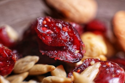 Close-up of a mixture of dried cranberries and almonds focused on the textures and colors. The cranberries are a vibrant red, appearing shiny and juicy, while the almonds are a natural beige, providing a contrasting texture.