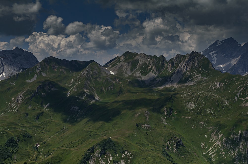 Grüne und schwarze Berge unter weißen Wolken und blauem Himmel tagsüber