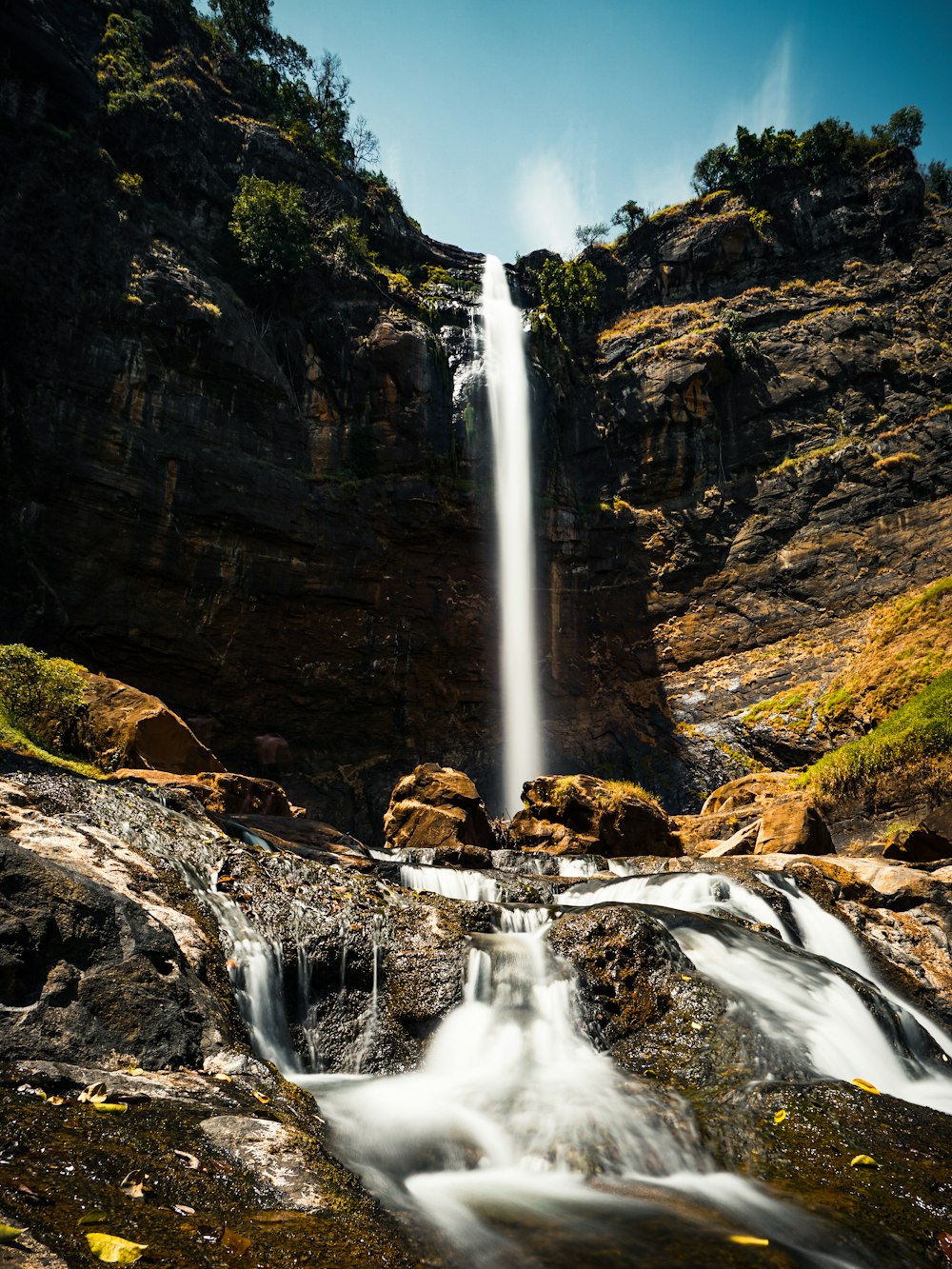 water falls on brown rocky mountain during daytime