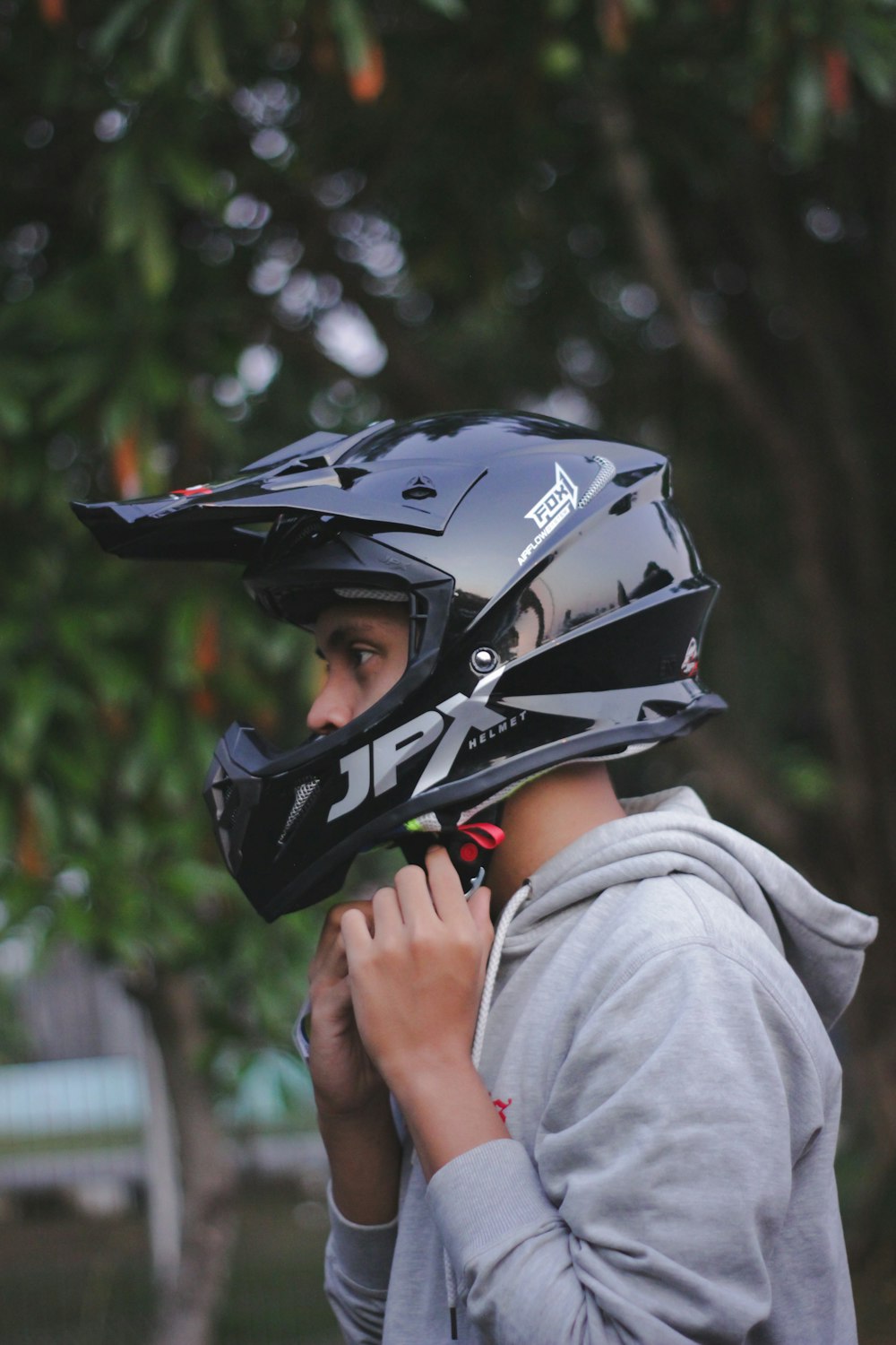 person in gray hoodie wearing black and red motorcycle helmet