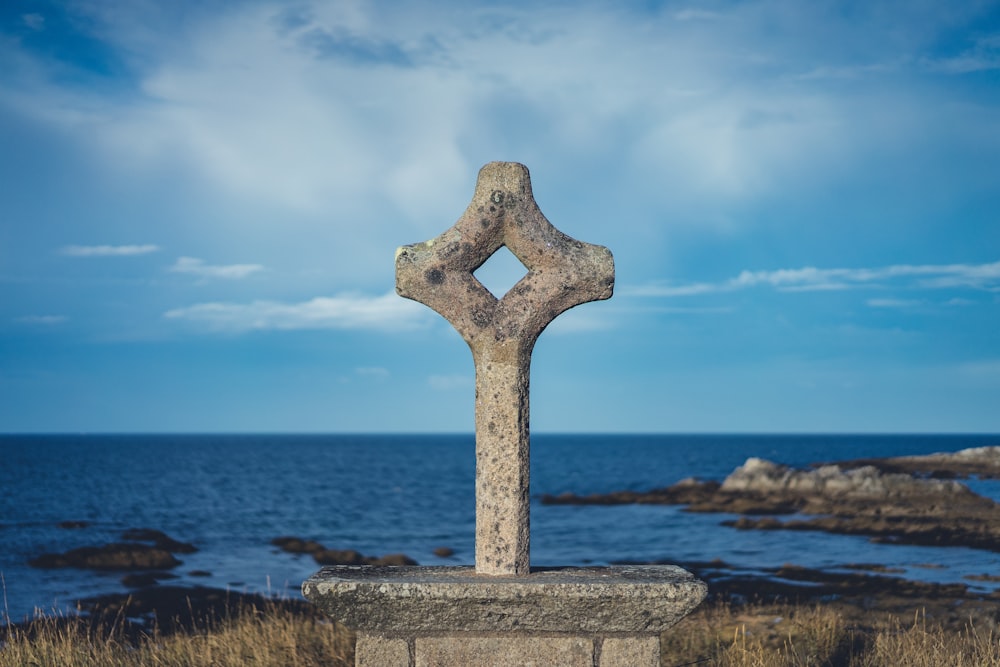 gray concrete cross on gray concrete surface near body of water during daytime