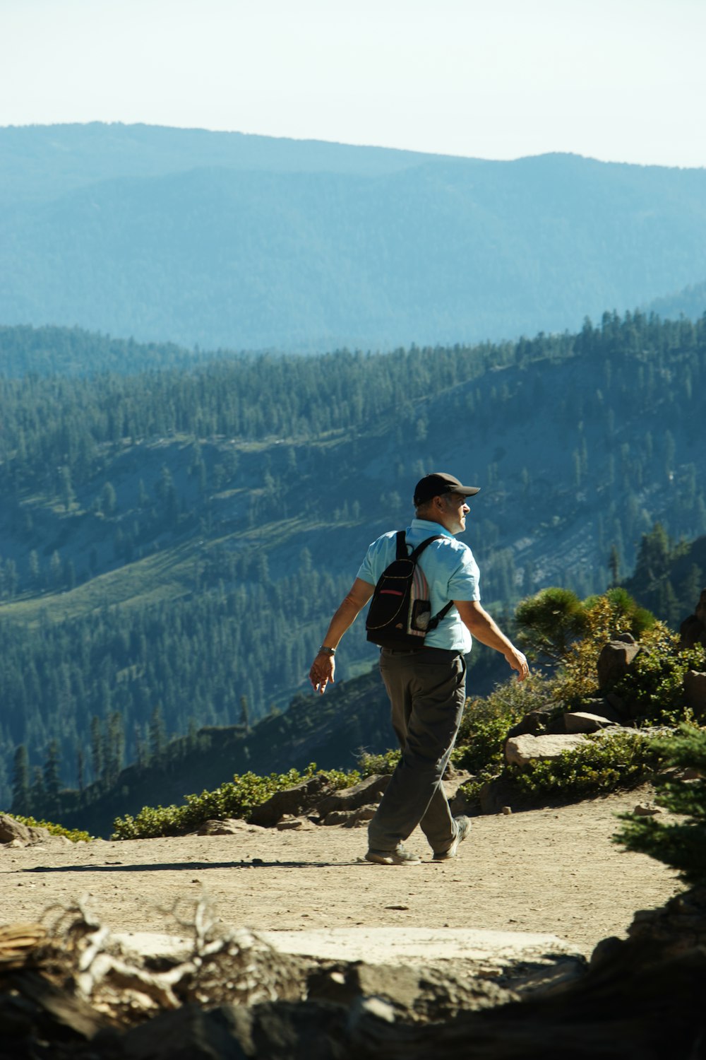 man in white t-shirt and black pants standing on rock during daytime