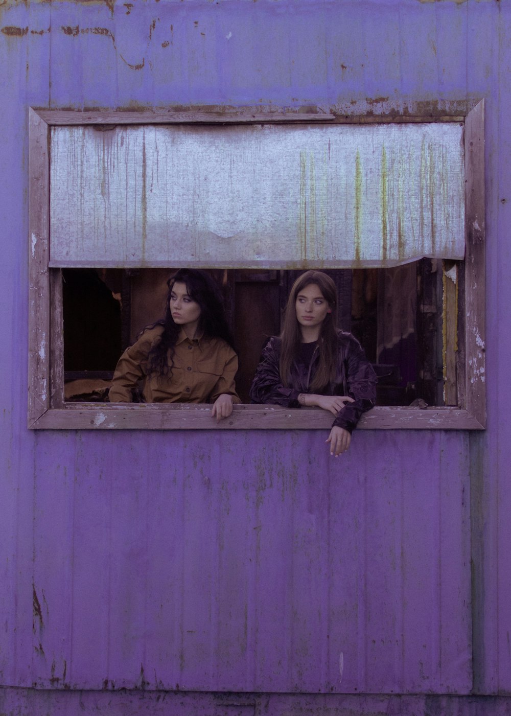 2 women sitting on window