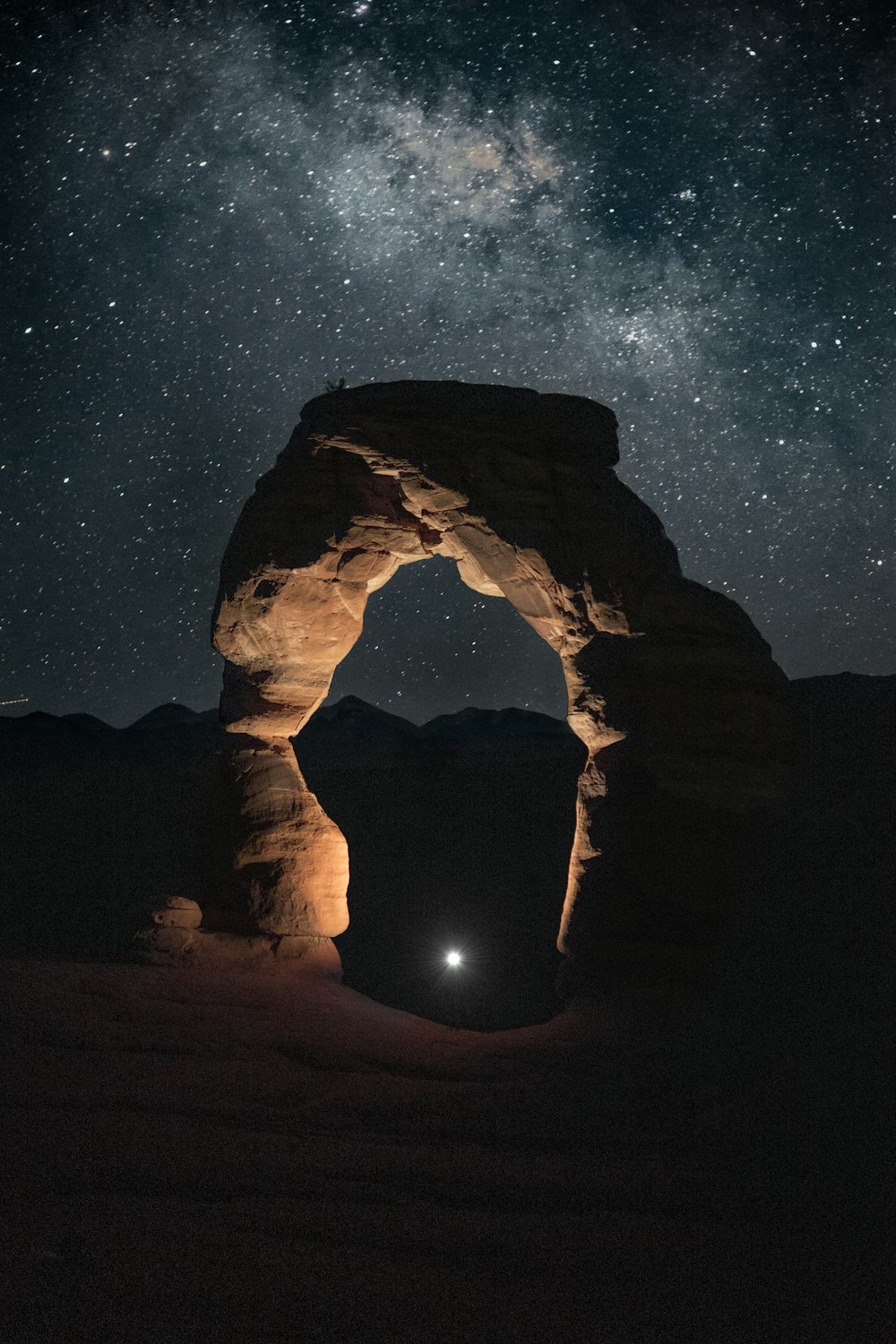 silhouette of man standing on rock formation during night time