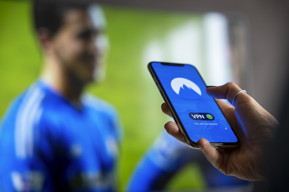 man in blue and white crew neck shirt holding black smartphone