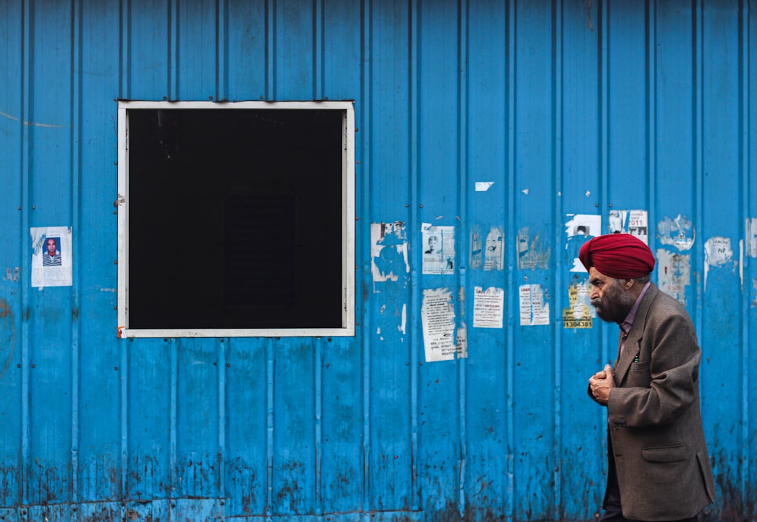 man in red cap standing beside blue wooden door