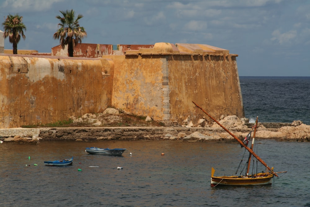 brown boat on sea near brown concrete building during daytime