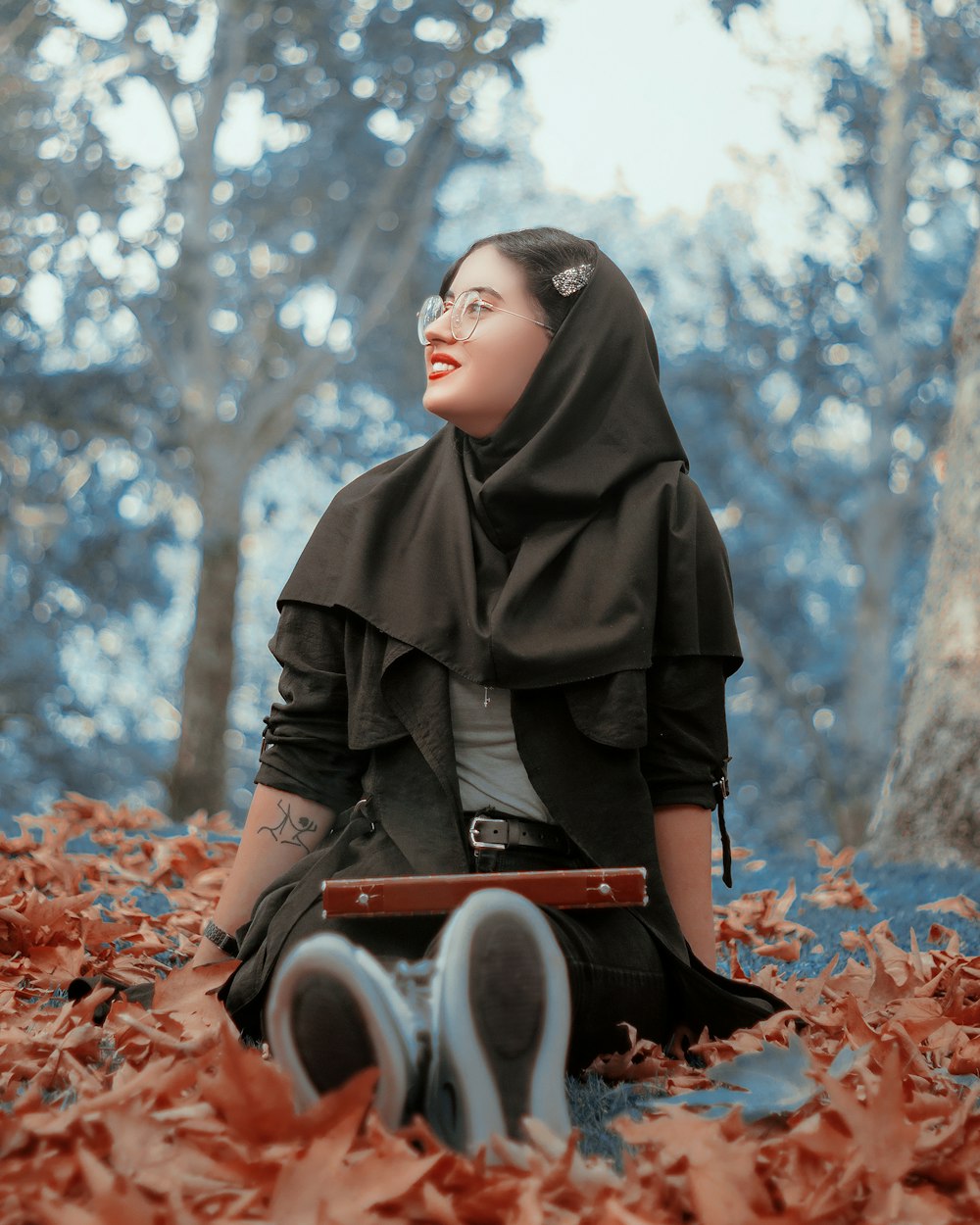 woman in black hijab holding black and red box