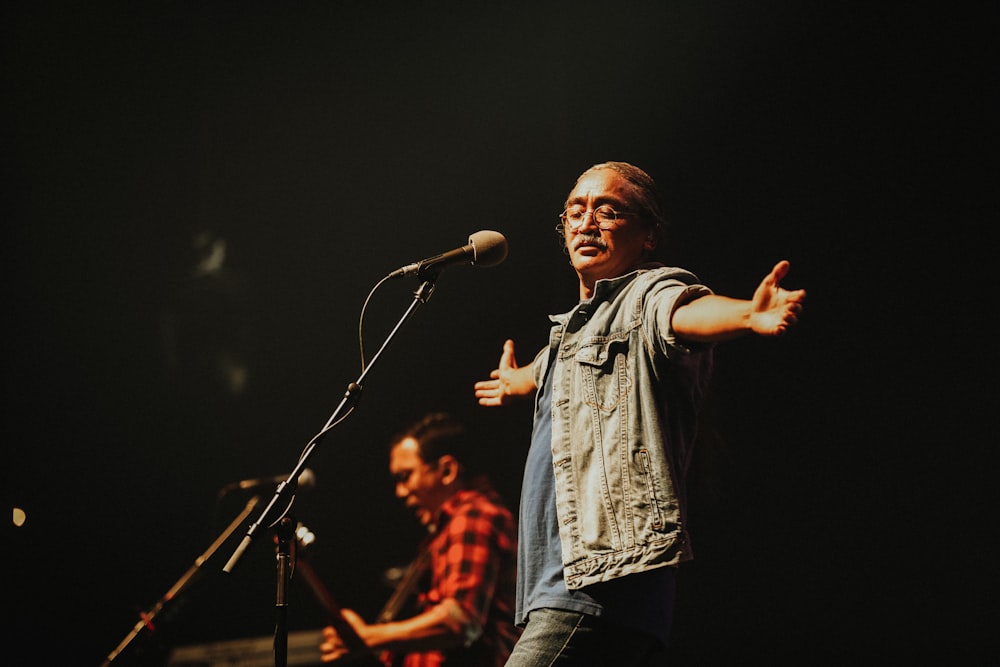 man in blue denim button up shirt singing on stage