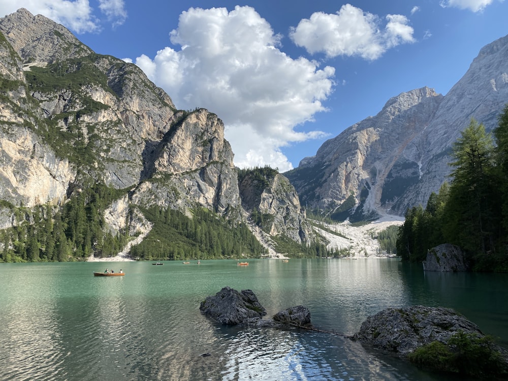 green and brown mountains beside body of water under blue and white sunny cloudy sky during