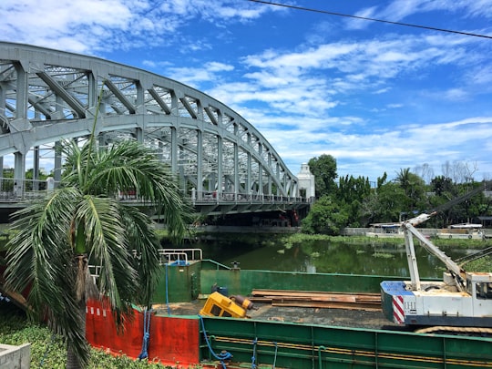 green and yellow boat on river near bridge under blue sky during daytime in Quiapo Philippines