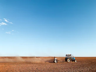 blue and black tractor on brown sand under blue sky during daytime