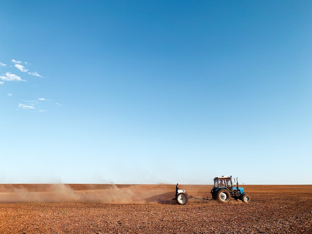 blue and black tractor on brown sand under blue sky during daytime