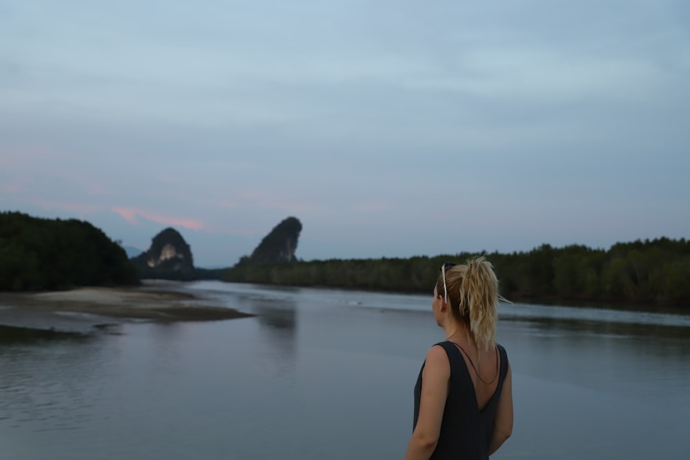 woman in black tank top standing near lake during daytime