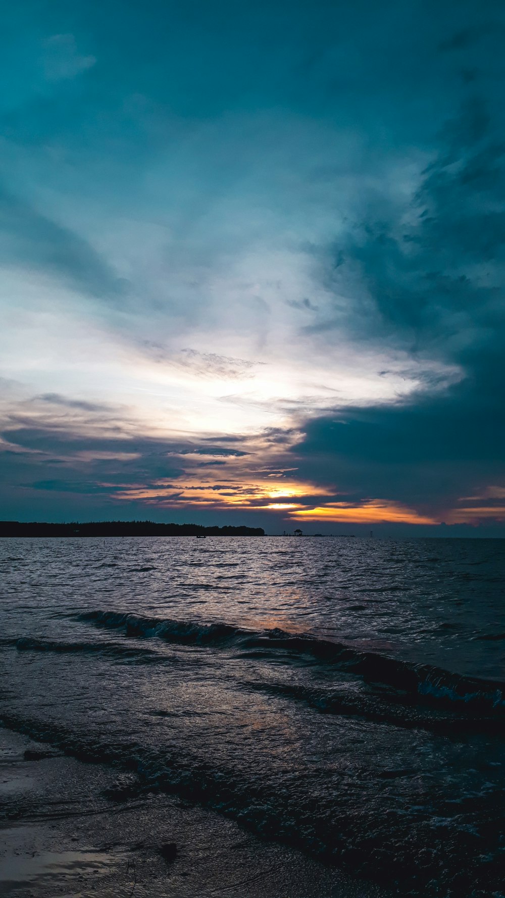 vagues de l’océan sous un ciel nuageux au coucher du soleil