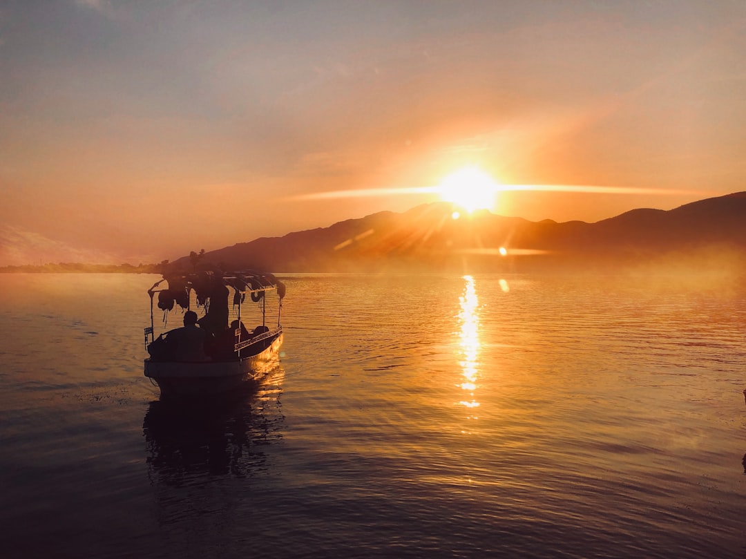 silhouette of people riding boat on sea during sunset