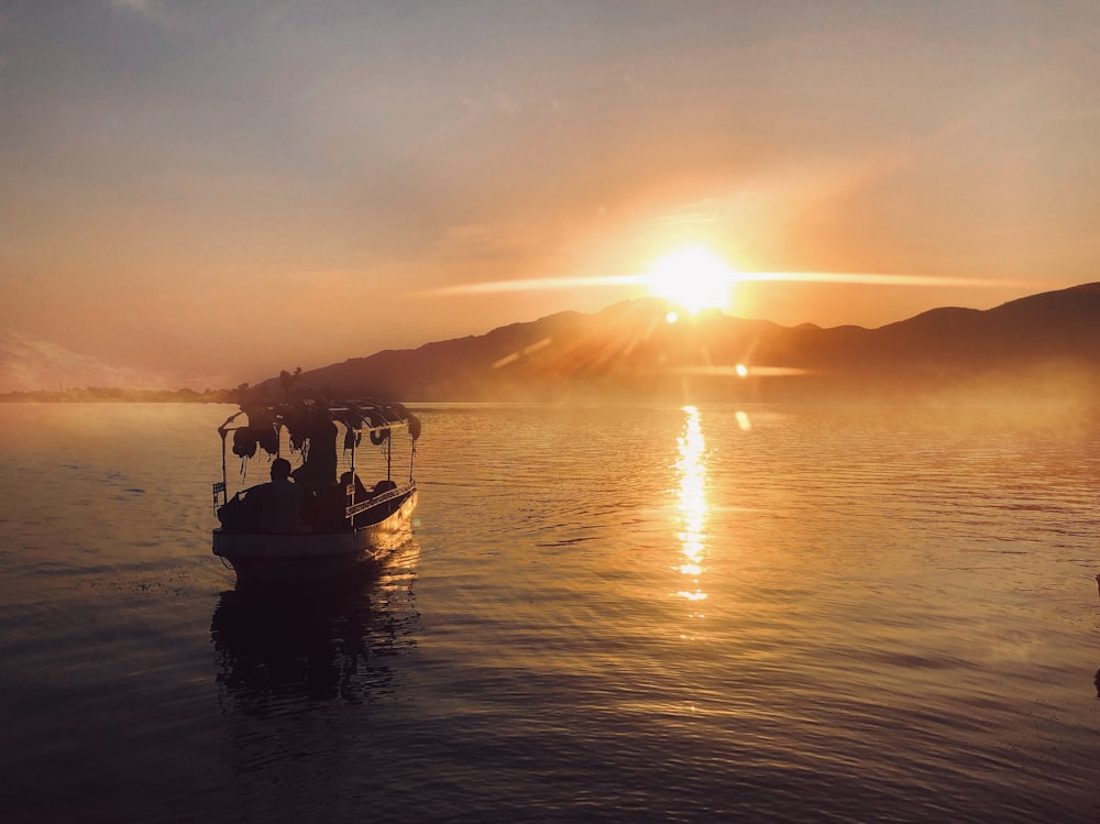 Silhouette von Menschen, die während des Sonnenuntergangs auf dem Meer fahren