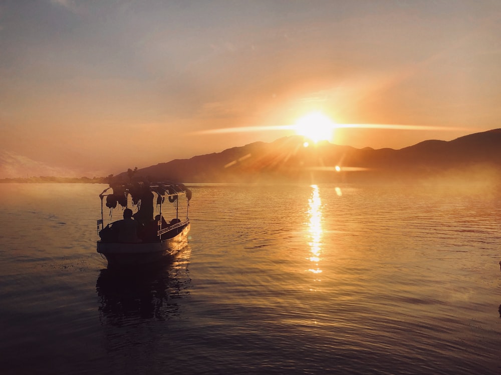 silhouette of people riding boat on sea during sunset