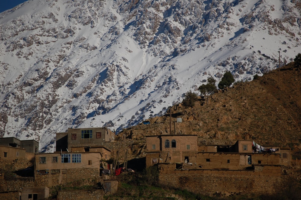 Edificio de hormigón marrón cerca de la montaña cubierta de nieve durante el día