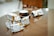 A wooden table with several packaged snacks featuring doodle-style art and the brand name 'Biscoman'. There is a black coffee cup with a white interior resting on the table. The background appears to be a cozy indoor setting with blurred elements.
